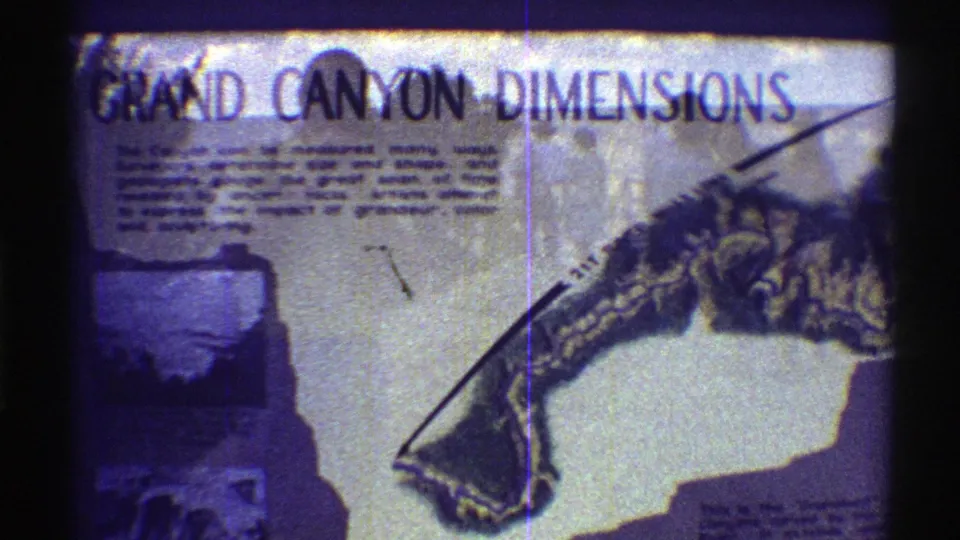1969 home-movie frame of a Grand Canyon Dimensions informational sign, with printed text, a canyon diagram, and an inset photograph.