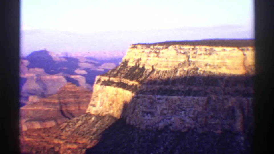 1969 Arizona home-movie view of the Grand Canyon, with layered cliffs and a bright mesa under a pale sky.