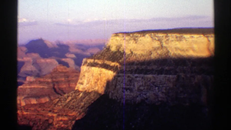 1969 Arizona travel frame showing Grand Canyon rock layers and a sunlit cliff edge from a visitor viewpoint.