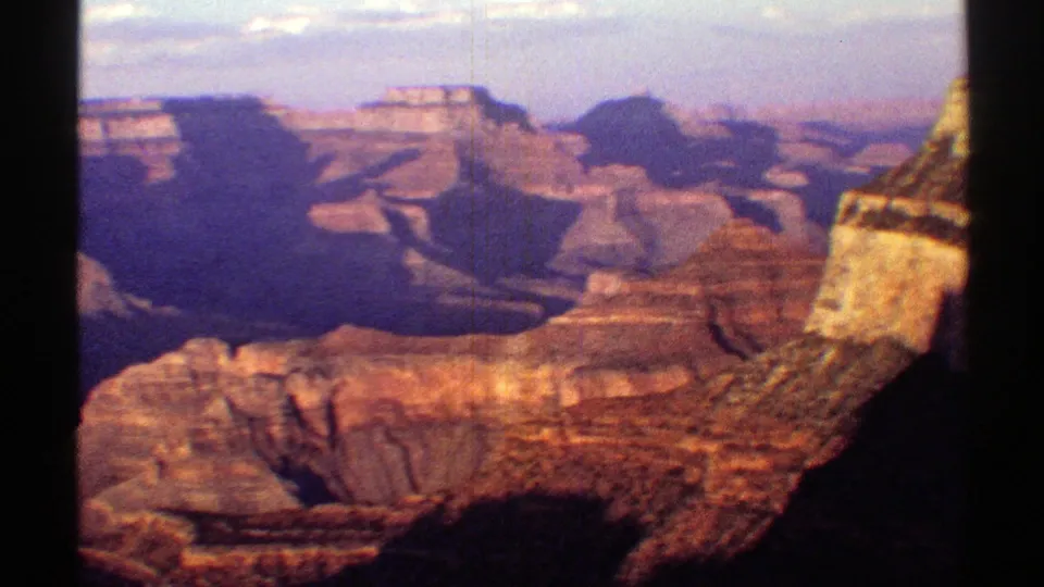 1969 8mm Arizona footage showing a wider Grand Canyon vista with deep shadows, layered mesas, red and tan rock, and visible film borders.