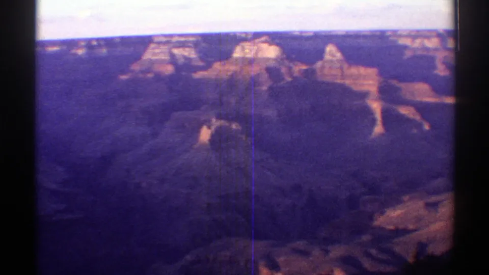 Late-1960s home-movie frame of the Grand Canyon, showing mesa-like formations, shadowed gullies, and warm highlights on canyon rock.