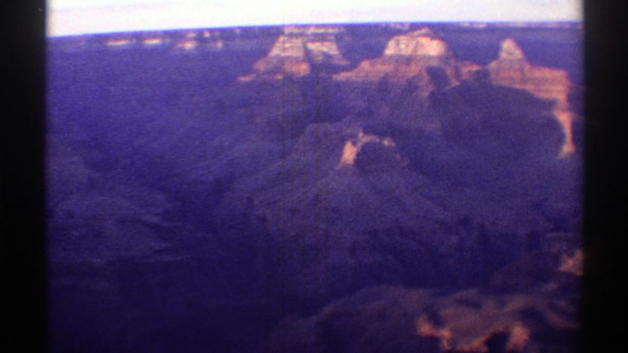 1969 Arizona 8mm view across a broad canyon with distant rock formations, purple color cast, and visible gate edges.
