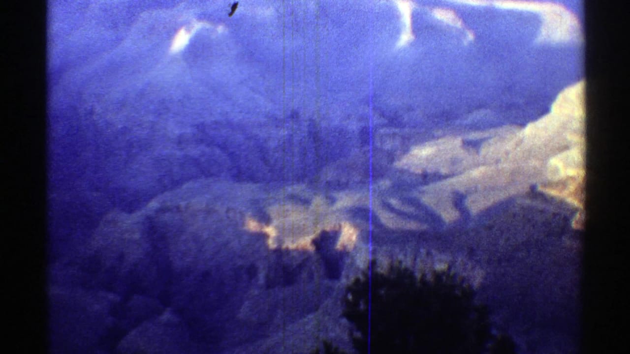 Soft blue-toned canyon view with dark film borders and distant rock formations.