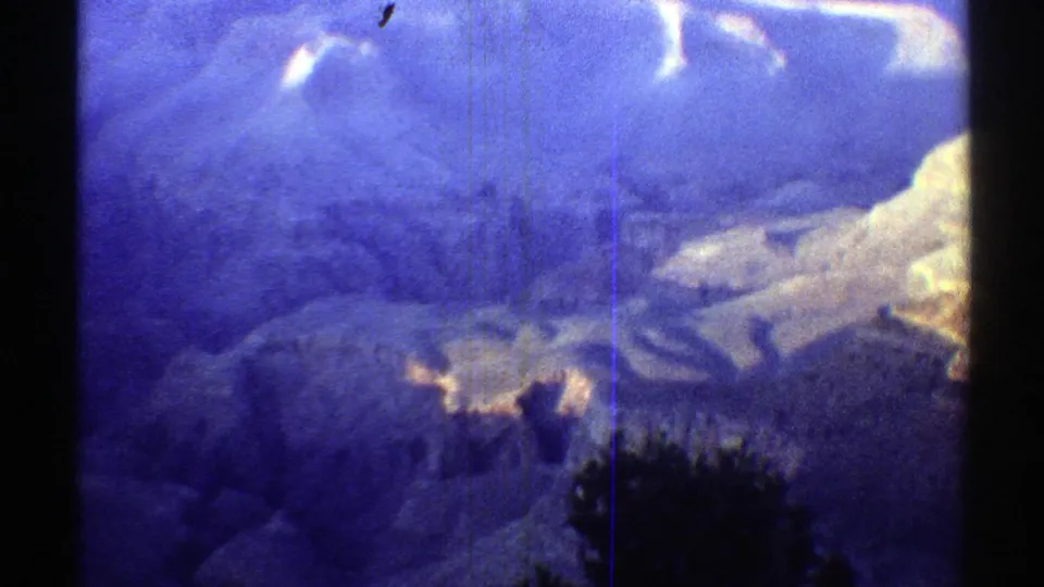 1969 8mm home-movie frame of the Grand Canyon in Arizona, with a blue color cast, dark gate edges, and hazy distant cliffs.