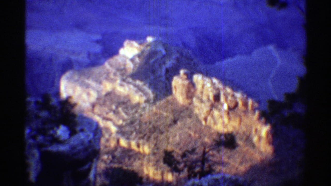 Warmly lit rock formation against deep blue twilight shadows with dark foreground silhouettes.