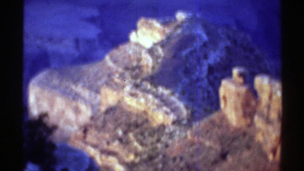 1969 Arizona home-movie frame with a close, hazy view of Grand Canyon stone shapes under a strong aged-film color shift.