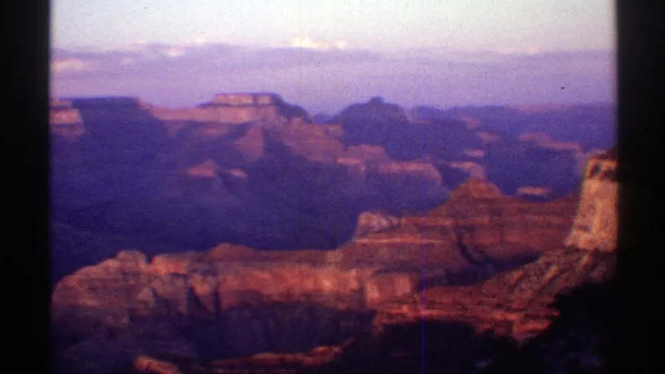 1969 Arizona home-movie frame looking across the Grand Canyon toward red rock layers, distant ridges, and a hazy horizon.