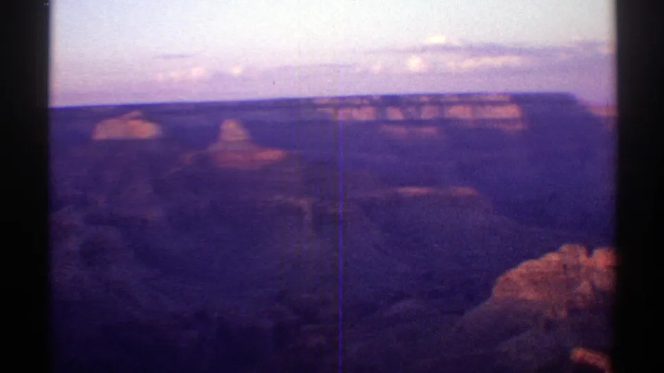 1969 Arizona dusk footage frame showing a shadowed canyon basin beneath a flat mesa horizon.