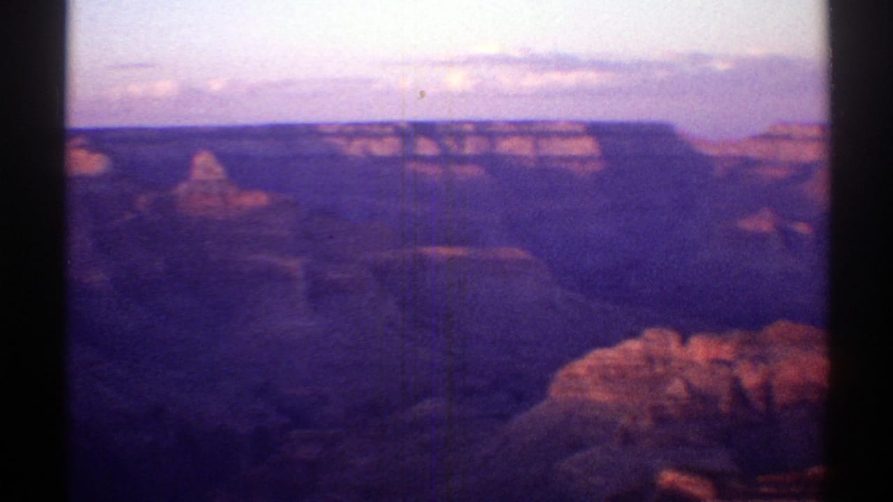 1969 Arizona 8mm frame showing the Grand Canyon with distant mesas, shadowed canyon walls, and warm evening light.