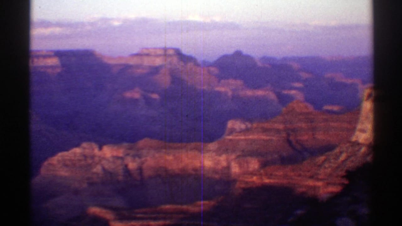 1969 Arizona canyon panorama with red rock formations, distant plateau shapes, and a dark frame edge from the 8mm scan.