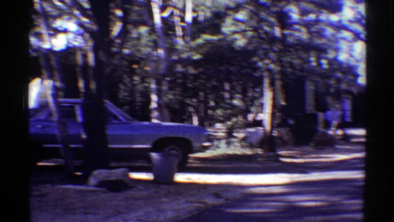 Station wagon and laundry line in a tree-shaded residential area, captured on 8mm film in Arizona, 1969.