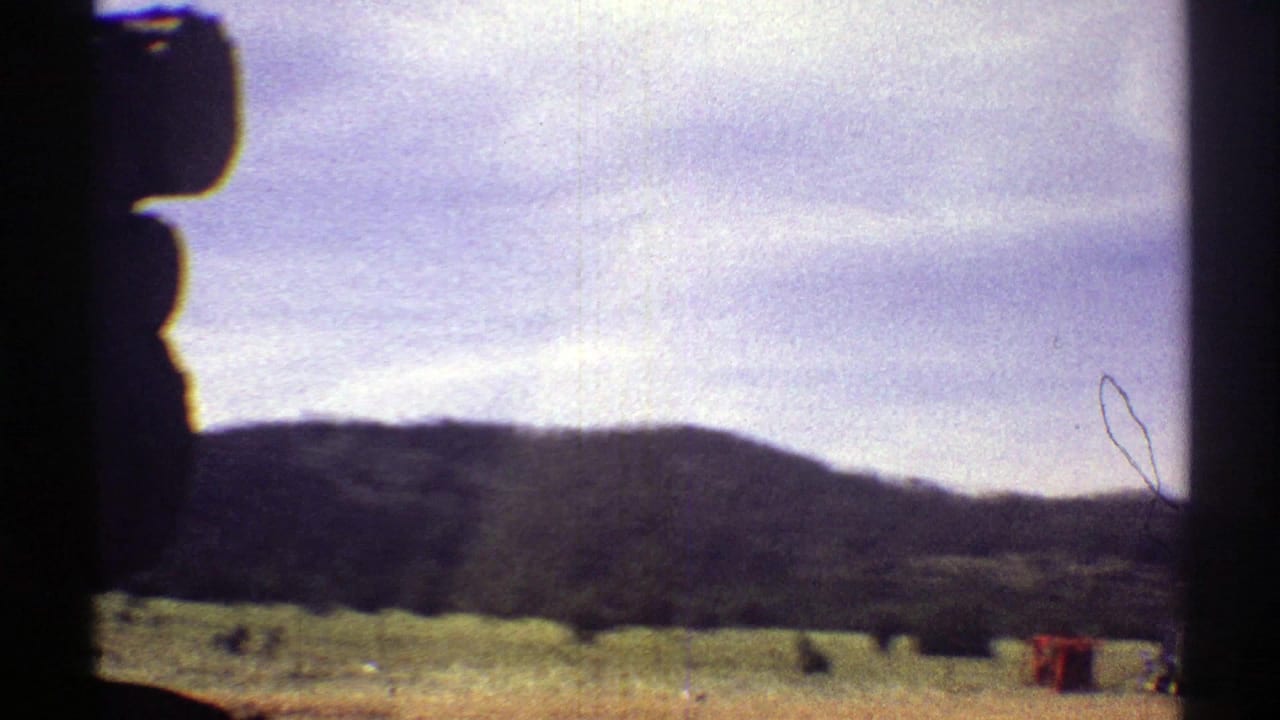Arizona 1969 home-movie frame showing distant hills and dry grassland through dark vehicle framing, with no people visible.