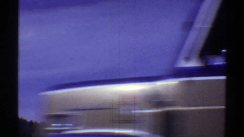 Arizona 1969 home-movie frame showing a blurred light-colored vehicle side passing close to the camera.