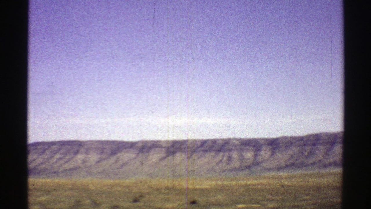 Long mountain ridge across the horizon with blurred grassland in the foreground.