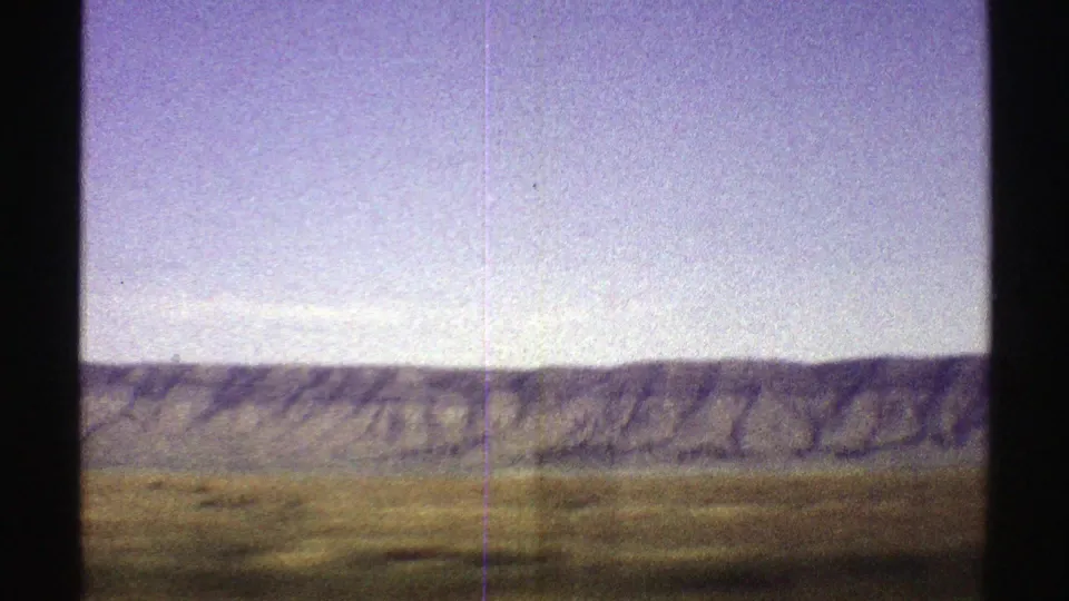 Final 1969 Arizona frame showing the mountain ridge stretching across the horizon as grassland blurs from vehicle motion.