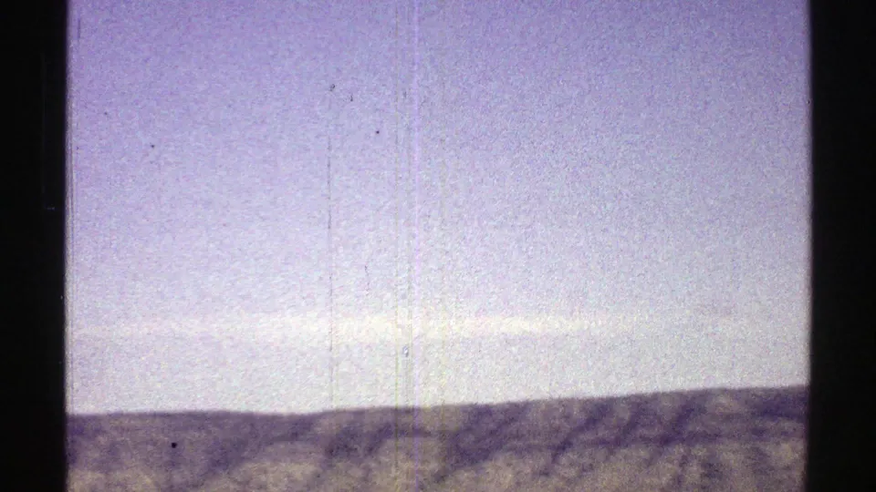 1969 Arizona desert landscape with a broad sky, distant ridge, softened horizon, and aged 8mm film texture.