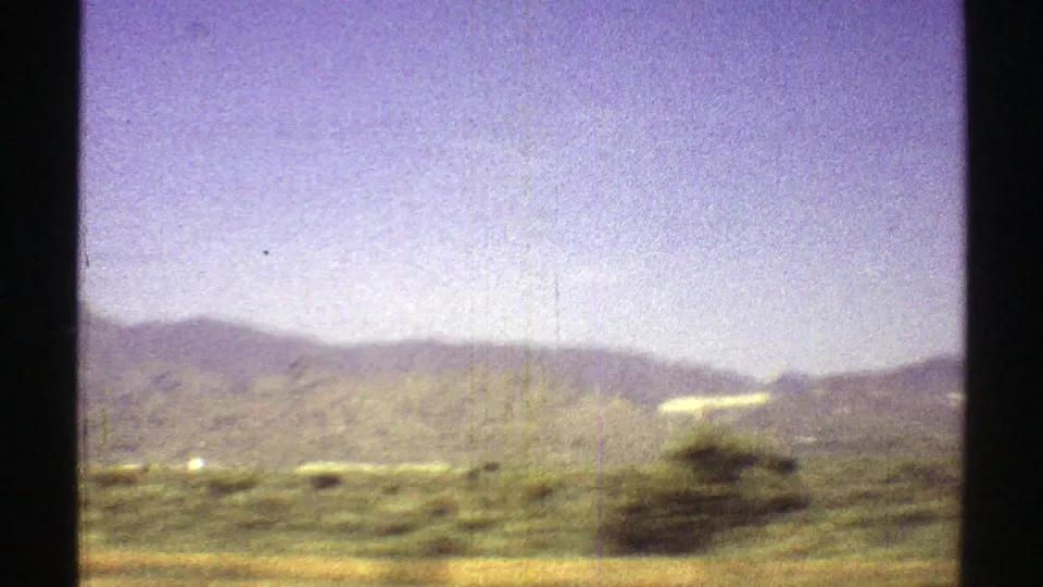 Arizona 8mm road-trip view from 1969 showing blurred roadside scrub, open desert, and soft distant mountains.