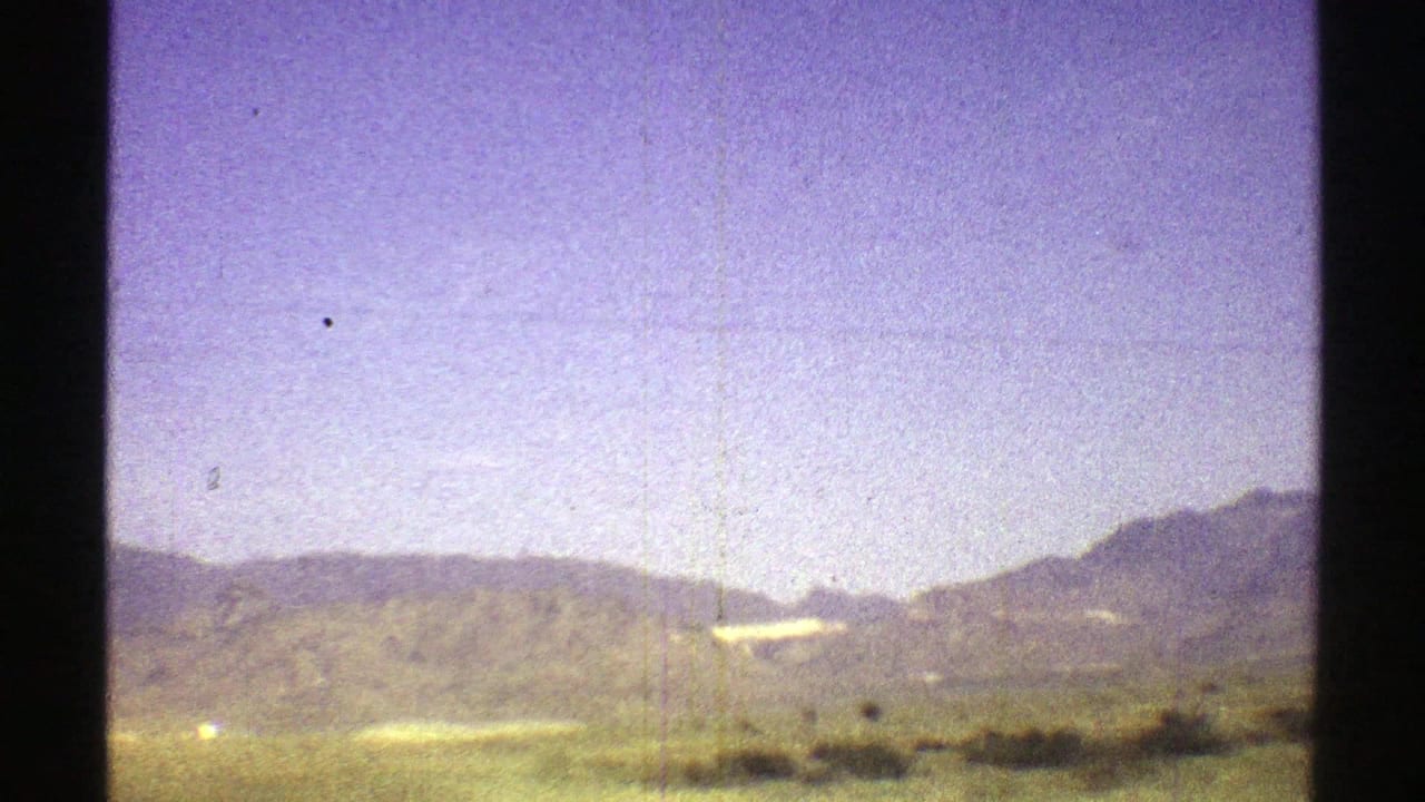 Arizona 1969 road-trip view of low desert hills and scrub passing in soft, grainy 8mm color.