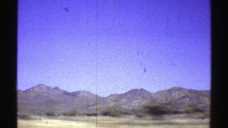 The final 1969 Arizona frame shows arid roadside terrain, scattered brush, and a continuous mountain range in soft 8mm color.