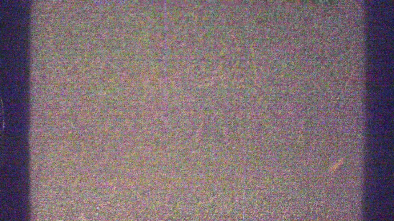 Dark-edged, grainy film frame with mostly mottled sky or overexposed landscape detail.