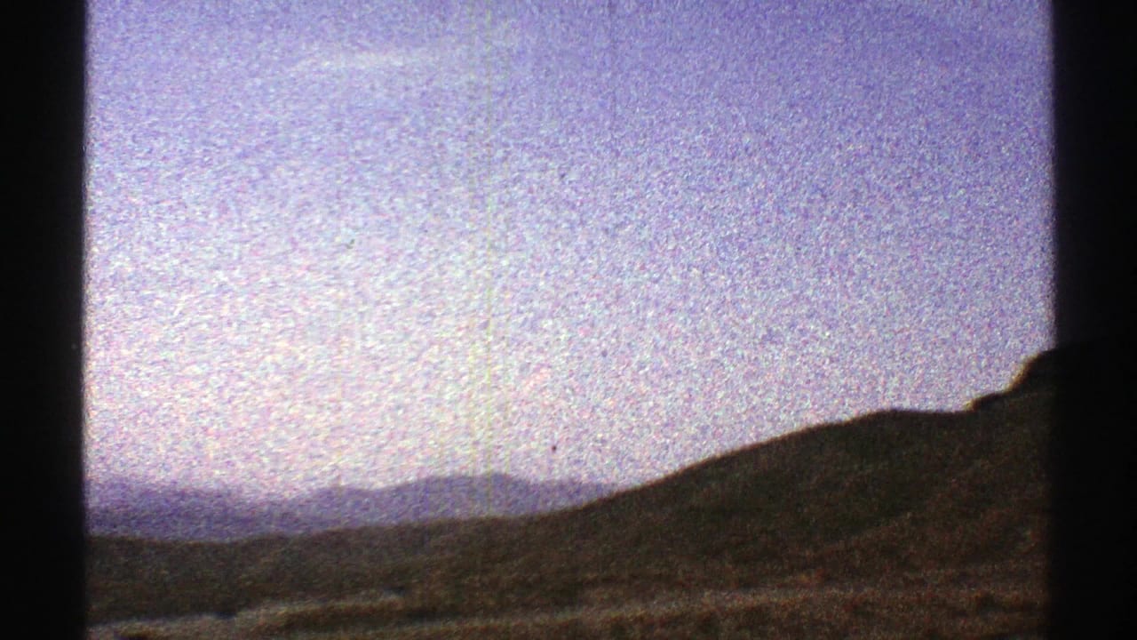 Rolling hillside and distant mountain ridges partly divided by dark vertical frame edges.