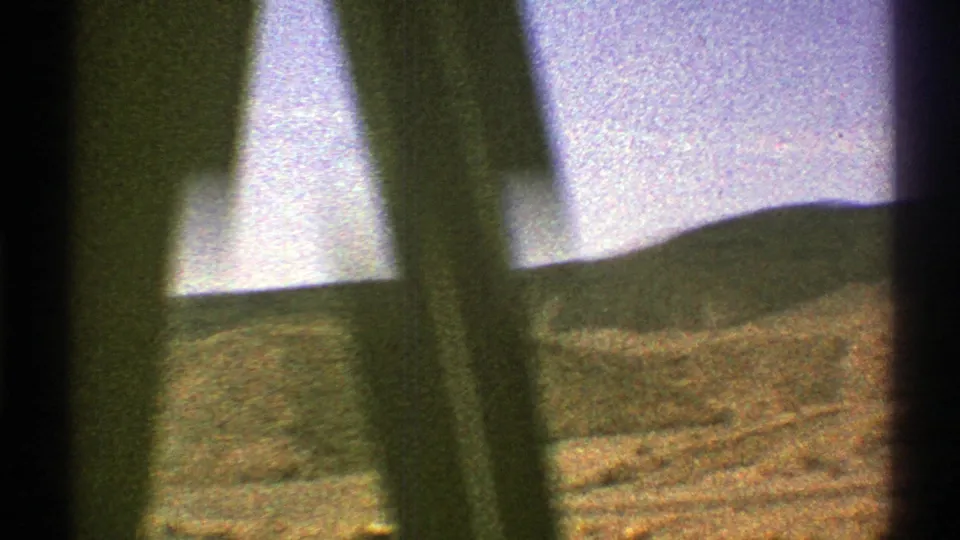 8mm home-movie view of dry Arizona hills with blurred foreground obstructions during vehicle motion.