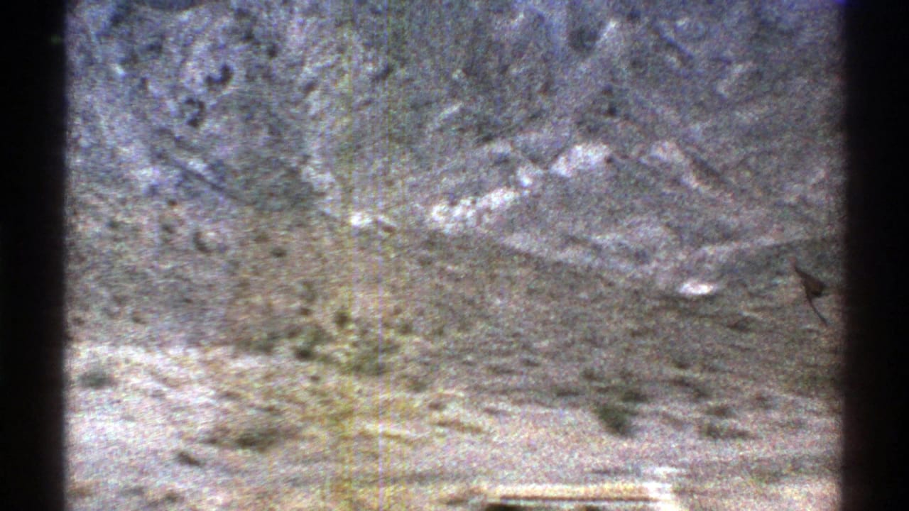 Rocky Arizona desert slope with sparse shrubs and washed 8mm color during the panoramic view.