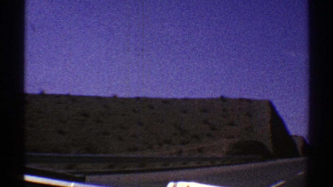 Roadside desert hill seen through a vehicle window with purple-blue sky.