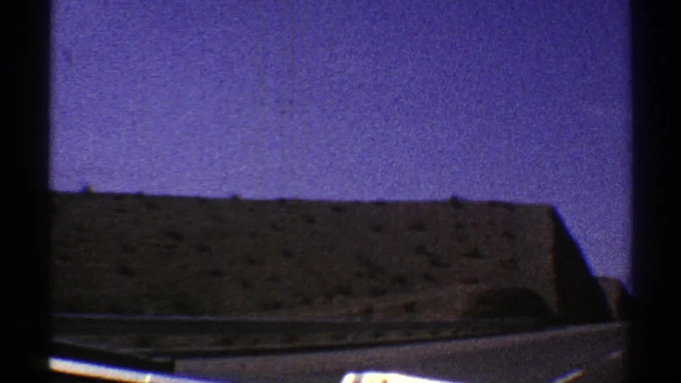 1969 Arizona 8mm frame showing a rocky desert hillside beside a road, viewed from inside a moving vehicle.
