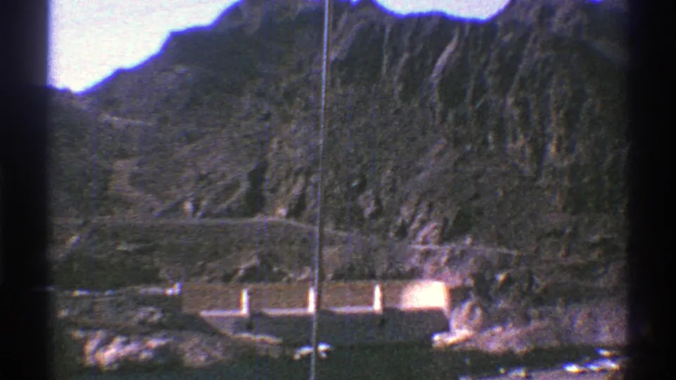1969 8mm view above Hoover Dam showing concrete structures, water, roads, and steep Arizona canyon walls.