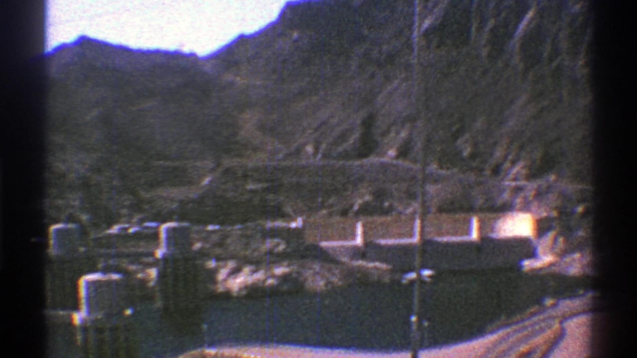 1969 Arizona home-movie frame looking across Hoover Dam facilities, water, and desert mountain terrain.