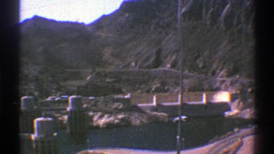1969 Arizona home-movie frame looking across Hoover Dam facilities, water, and desert mountain terrain.