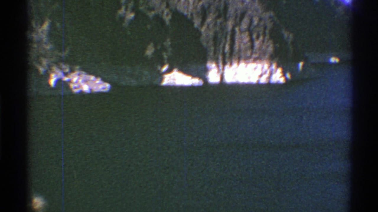 Faded 8mm view of an Arizona lake and pale rock shoreline with dark mountain terrain in the distance.