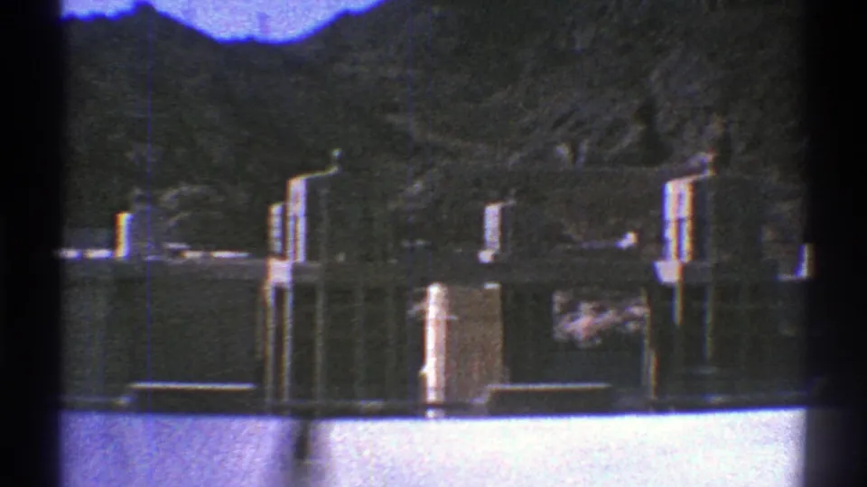 8mm frame of Hoover Dam towers, concrete infrastructure, reservoir water, and rocky Arizona canyon slopes.