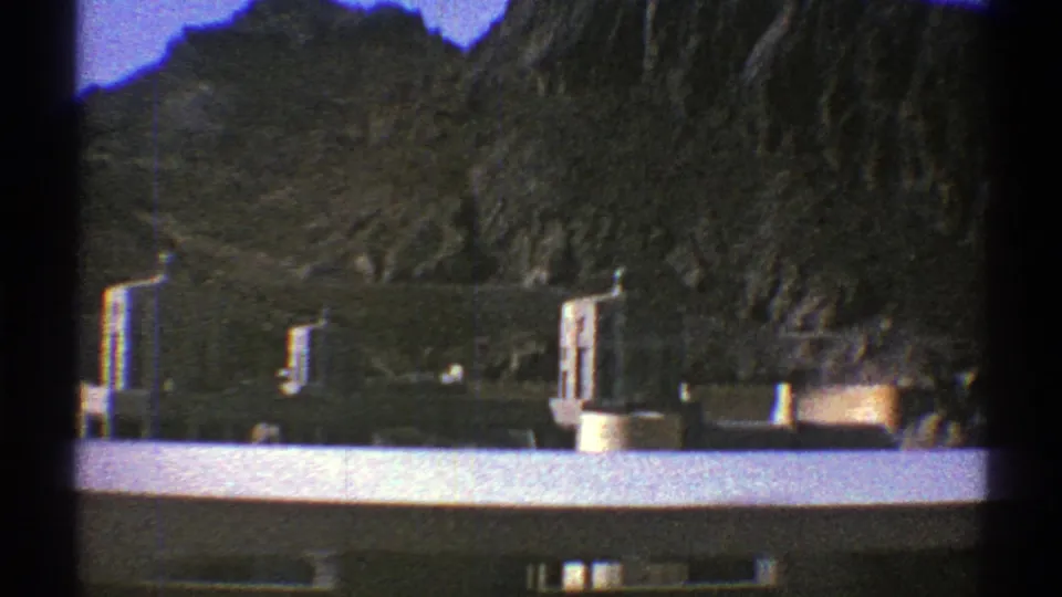 Late-1960s 8mm view of Hoover Dam intake structure and reservoir water beneath steep desert canyon walls.