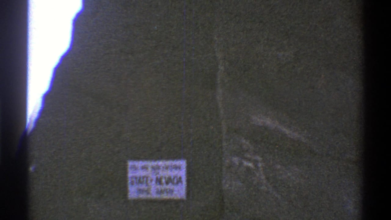 1969 8mm frame showing a Nevada state-entry safety sign filmed close-up during a Southwest road trip.