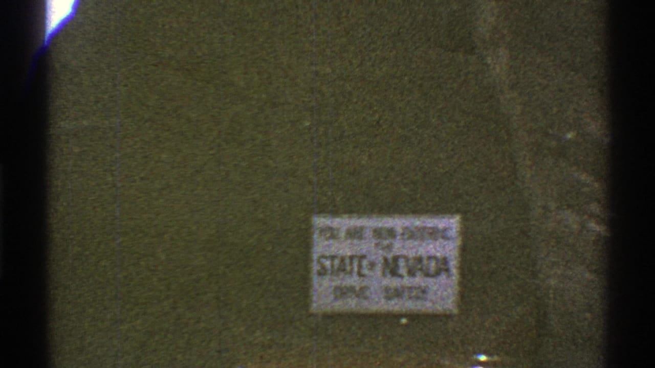 Close 8mm view of a sign reading that the viewer is entering Nevada, with faded color and soft focus.