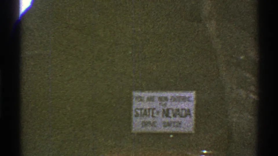 Close 8mm view of a sign reading that the viewer is entering Nevada, with faded color and soft focus.