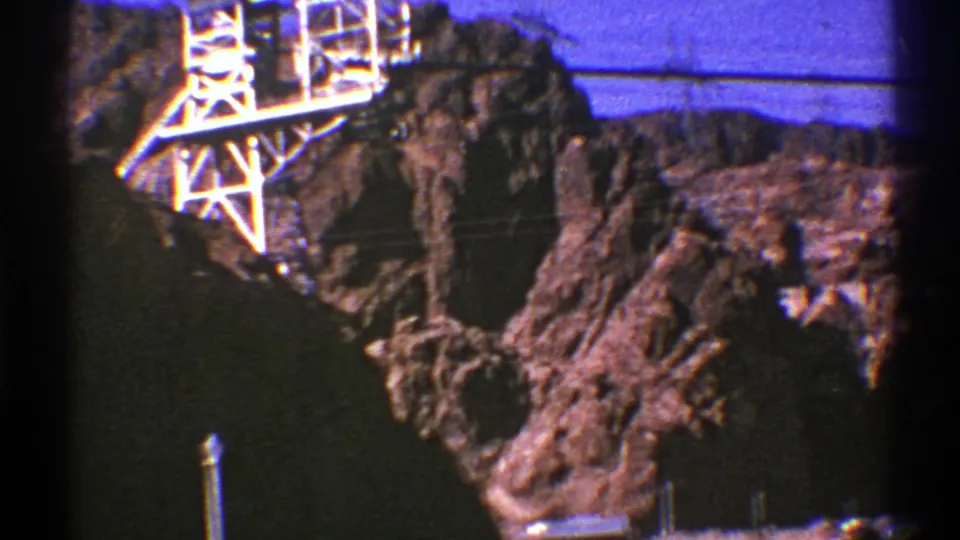 1969 8mm roadside view of rugged Southwest rocks with a white electrical transmission tower above the cliff.