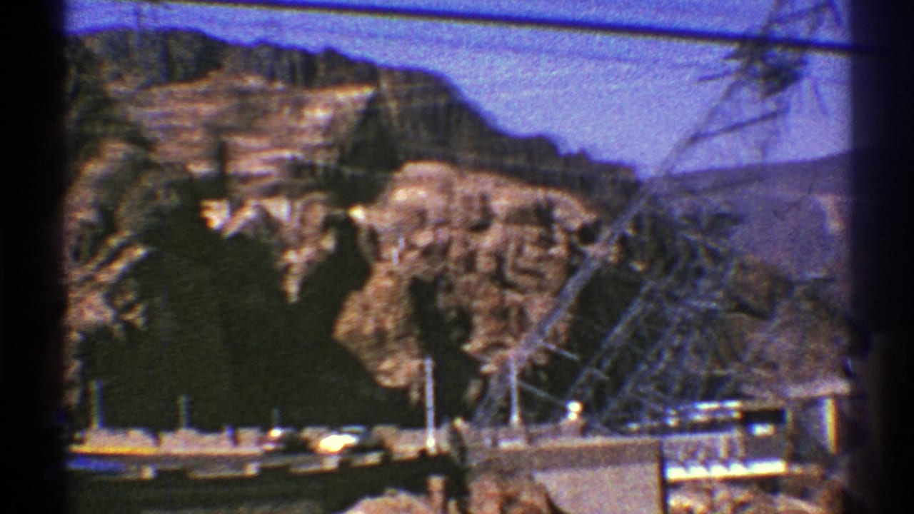 Brown canyon mountains with a steel power tower and dam structure in the foreground.