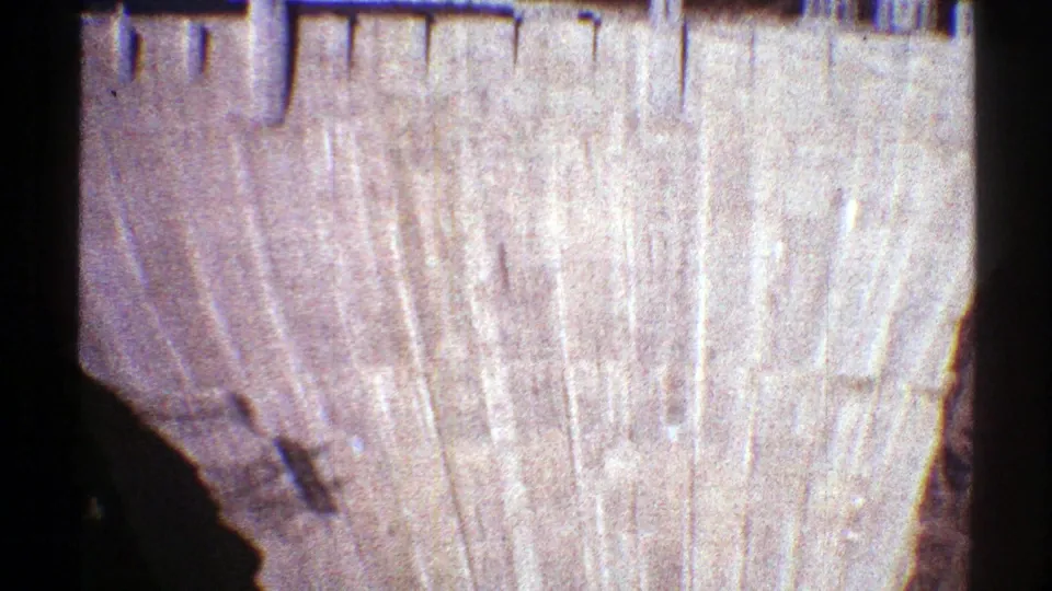 1969 Arizona home-movie frame showing the broad concrete dam face beneath rugged rock formations.