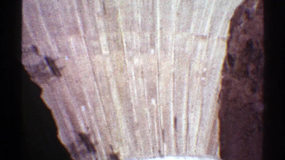 Late-1960s 8mm frame showing Hoover Dam's concrete face, vertical surface marks, and a dark canyon wall at the side.