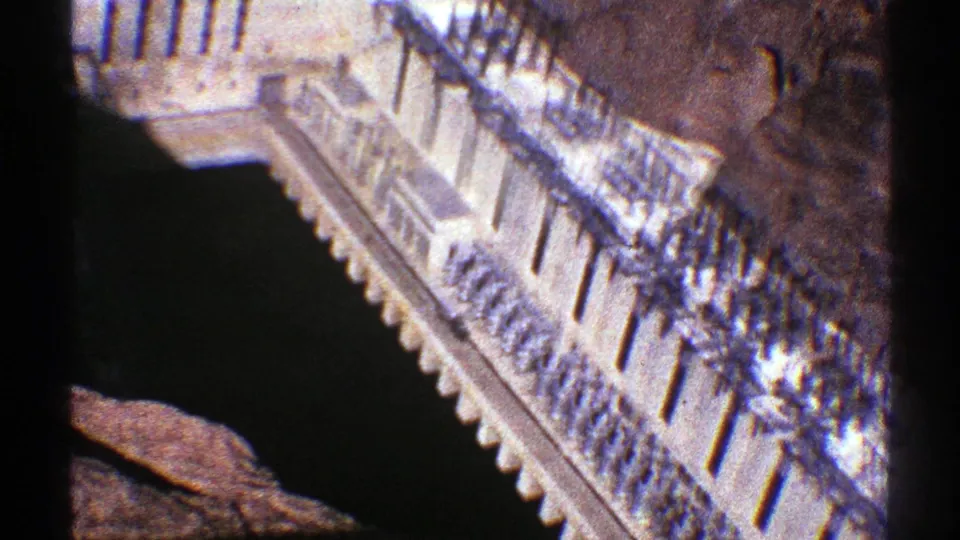 1969 Arizona 8mm frame showing a pale stepped building with railings seen from a high overlook near a rocky cliffside.