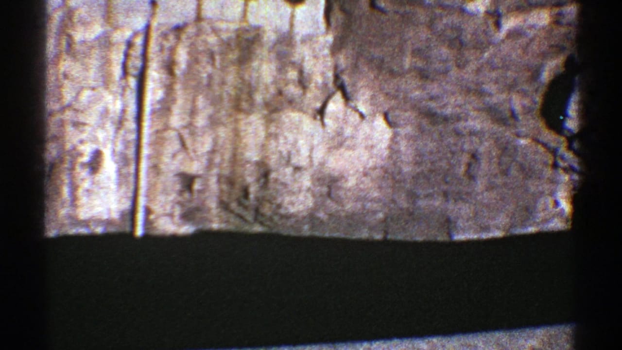 Aerial 8mm view of Arizona rock formations and dark water, with prominent frame division and soft vintage color.