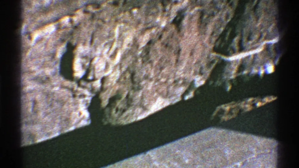 1969 Arizona home-movie aerial view looking down on rugged cliff textures and a narrow dark river channel.