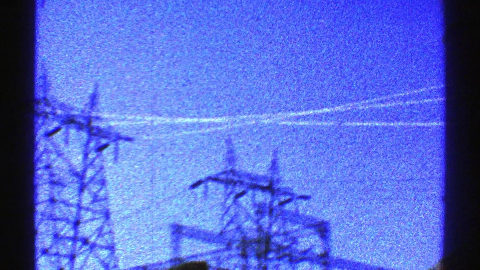 1969 Arizona 8mm view of power-line structures near the lower edge of a grainy blue dusk frame.