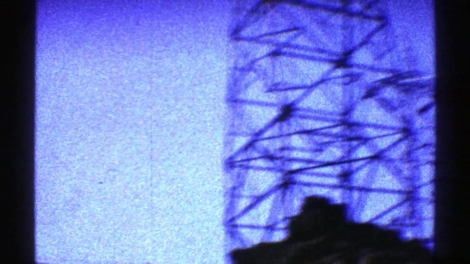 1969 Arizona 8mm frame with a closer, blurred lattice tower silhouette and power lines against blue dusk light.