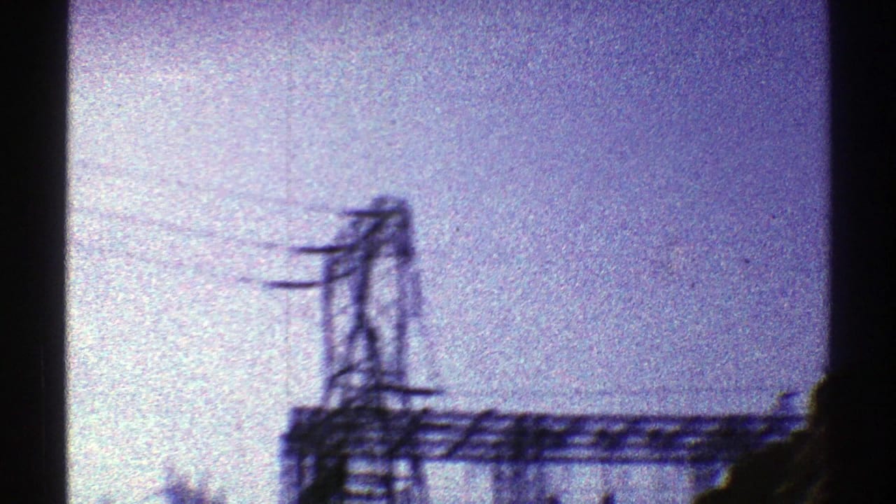 1969 Arizona 8mm frame showing a dark lattice transmission tower and overhead wires against a purple-tinged sky.