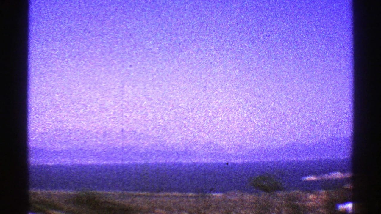 Blue-purple sky above a faint horizon, framed by dark vertical edges and grain.