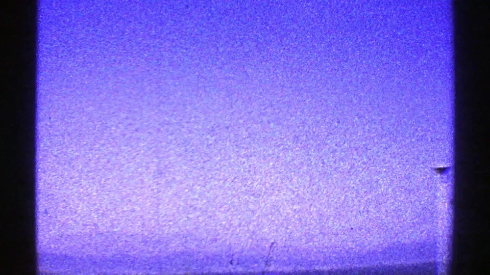 1969 Arizona 8mm frame showing a grainy blue-purple sky with dark edge framing and a faint horizon or exposure band.
